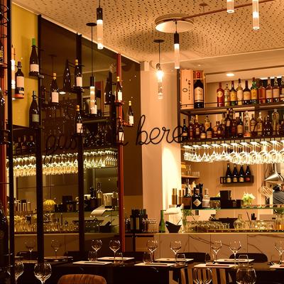 Bancone bar illuminato con lampade sospese, bottiglie in esposizione e atmosfera calda - impianto luci realizzato da Disco Express