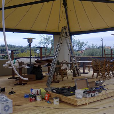Gazebo in fase di allestimento con scala, strumenti e arredi impilati.